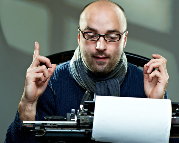 Старомодный лысый писатель в очках пишет книгу на винтажной пишущей машинке
