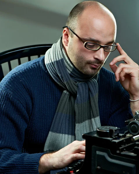 Ancienne chauve écrivain dans des lunettes écriture livre sur une machine à écrire vintage — Photo