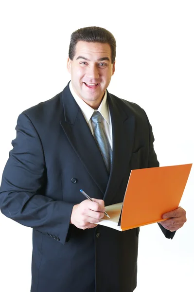 Ελκυστική άνθρωπος με μαύρο κοστούμι με πορτοκαλί βιβλίο και στυλό απομονωμένες o — Φωτογραφία Αρχείου