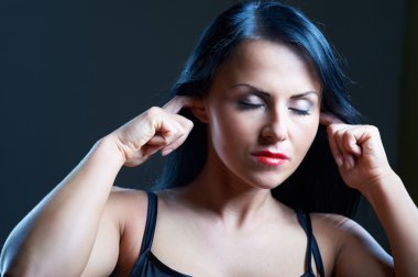 I Can't Hear You. Portrait of young woman in darkness covering her ears clipart