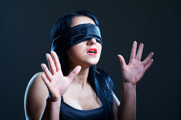 Portrait of young woman in darkness with covered eyes