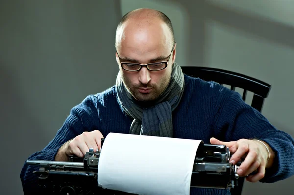一个秃头的作家坐在一台打字机的肖像 — 图库照片