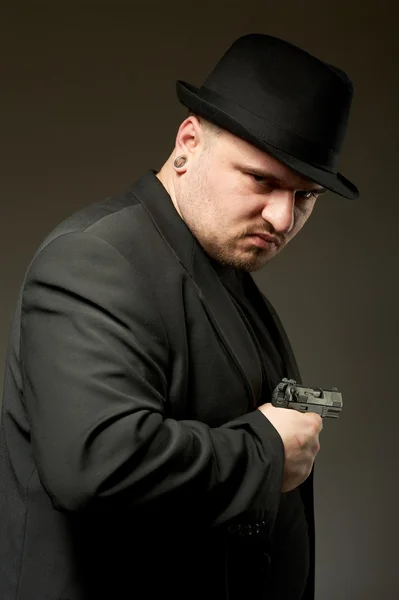 Muž v černém suite s pistolí. — Stock fotografie