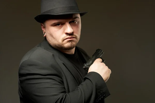 Man in zwarte suite met pistool. — Stockfoto