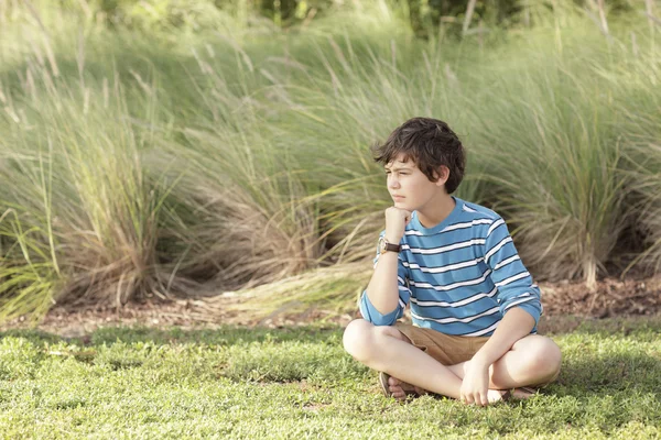 Pojken som sitter i ett fält — Stockfoto