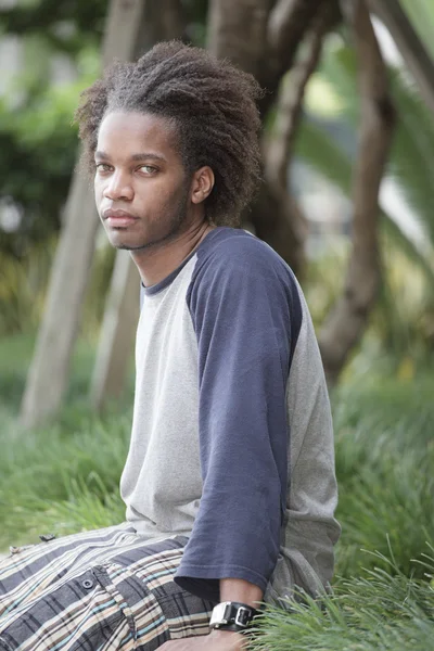 Νεαρό μαύρο αρσενικό που κάθεται στο πάρκο — Φωτογραφία Αρχείου