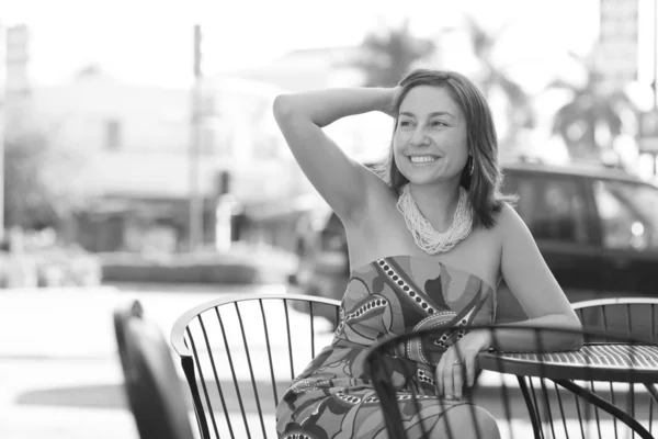 Vrouw zitten aan een tafel en glimlachen — Stockfoto