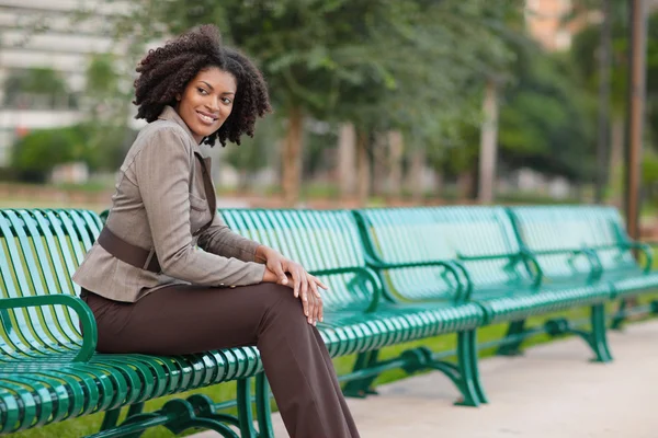 女人坐在公园的长椅上 — 图库照片