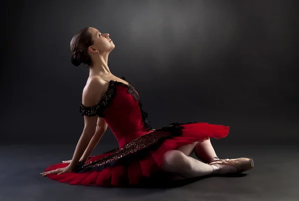 Балерина сидит на черном фоне — стоковое фото