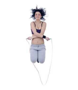 Woman standing in gym wear jumping with skipping rope clipart