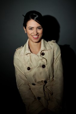 Woman wearing a trench coat and smiling clipart