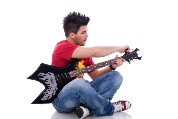 Guitarrista sentado calibrando sua guitarra — Fotografia de Stock