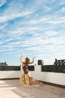 güzel genç dansçı Yoga-dans açık mavi gökyüzü ve bulutlar ile arka planda gerçekleştirme