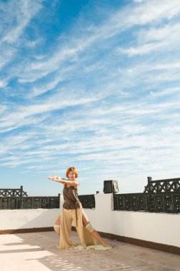 güzel genç dansçı Yoga-dans açık mavi gökyüzü ve bulutlar ile arka planda gerçekleştirme