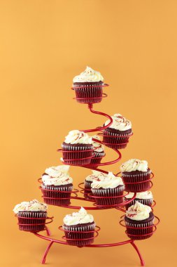 Red velvet cupcakes in a red cupcake holder against a yellowish orange background with copy space included. clipart