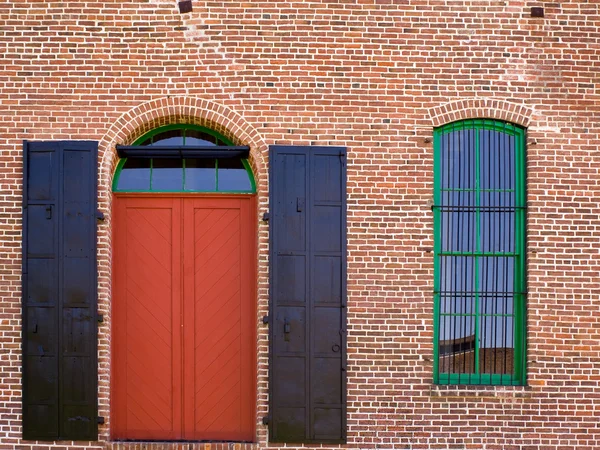 Τούβλινο τοίχο με κόκκινη πόρτα και παράθυρο — Φωτογραφία Αρχείου