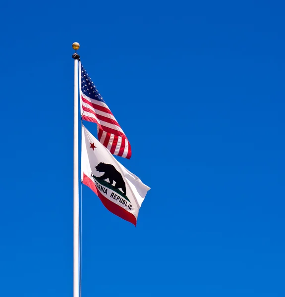 Amerikanische und kalifornische Flaggen wehen vor einem strahlend blauen Himmel — Stockfoto