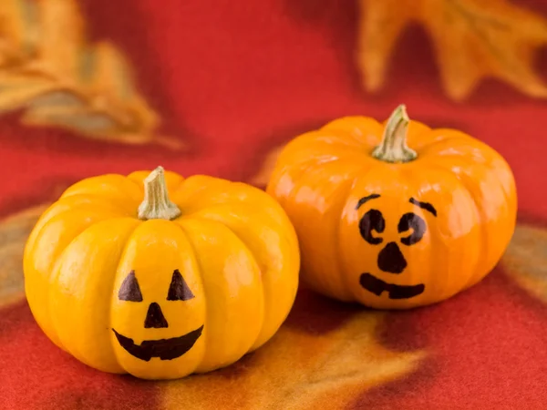 Mini Pumpkins with Funny Faces on a Red Autumn Cloth Background — Stock Photo, Image