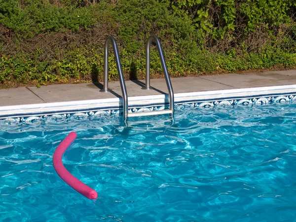 Piscina Azul. Escada, e brinquedo de piscina rosa em plena luz do sol — Fotografia de Stock