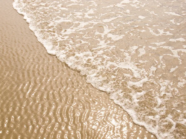 Schuimend Oceaan kustlijn op een zonnig strand — Stockfoto