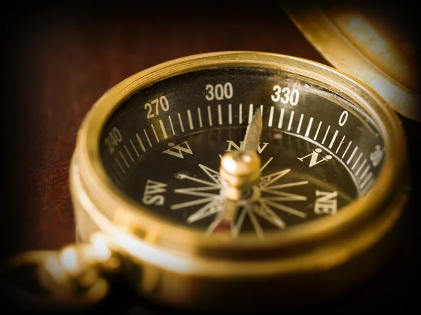 stock image Brass Compass on an old cherrywood table with a dark border