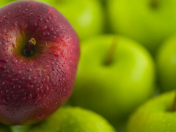 绿色苹果用一个单一的红色美味的背景 — 图库照片
