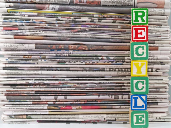En hög med tidningar med ordet återvinna i alpahbet svarta — Stockfoto