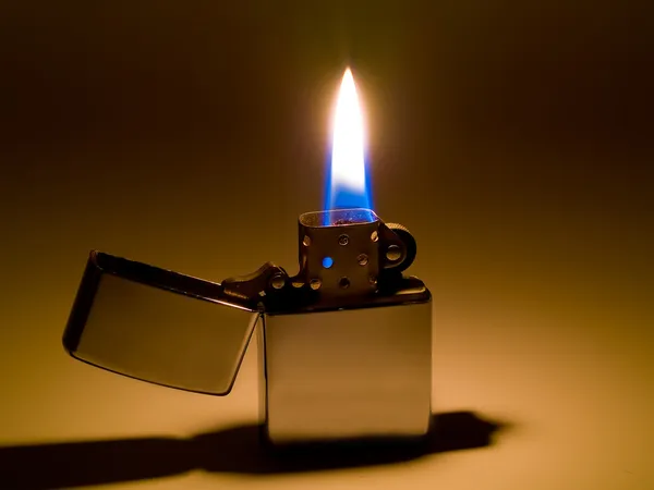 A cigarette lighter with a yellow and blue flame — Stock Photo, Image