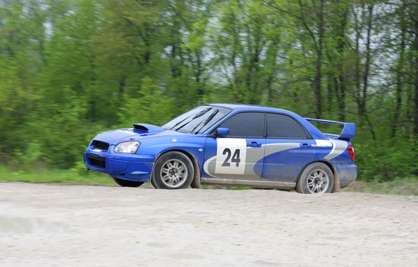Блакитна гоночна ралі машина на мокрій гравійній дорозі — стокове фото