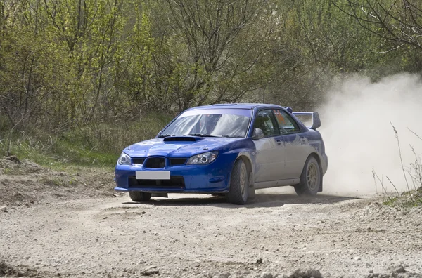 Blaues Rallye-Auto auf Schotterpiste lizenzfreie Stockbilder