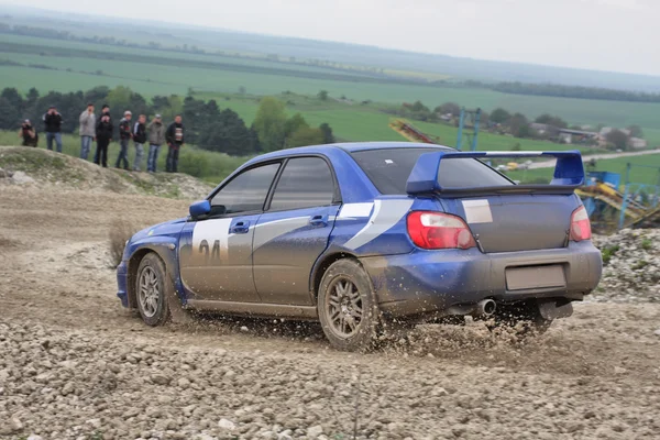 Blue racing rally car on wet gravel road Stock Photo