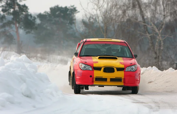 Röda och gula bil i rally på snö spår Stockbild