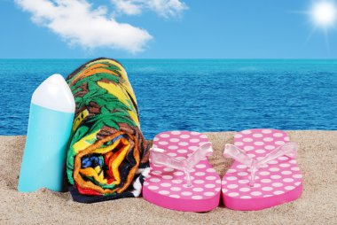 Closeup beach with sandals towel and suntan lotion clipart