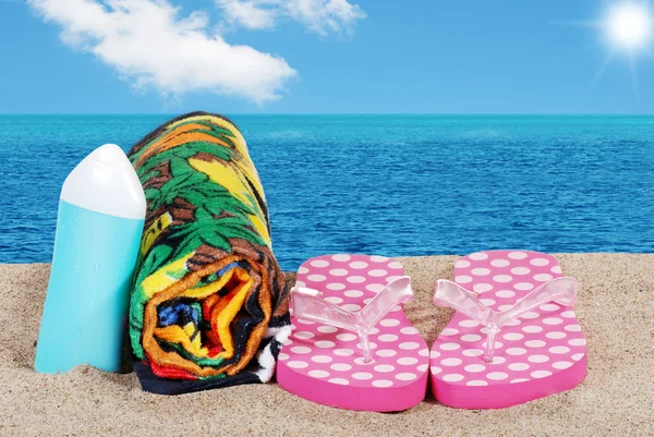 Closeup beach with sandals towel and suntan lotion — Stock Photo, Image