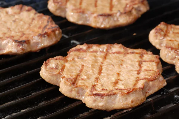DOF raso de hambúrgueres em uma grelha de churrasco — Fotografia de Stock