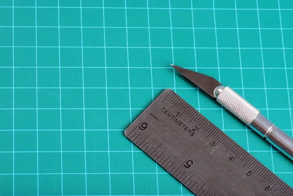 Ножі лінійки на зеленому ріжучому килимку — стокове фото