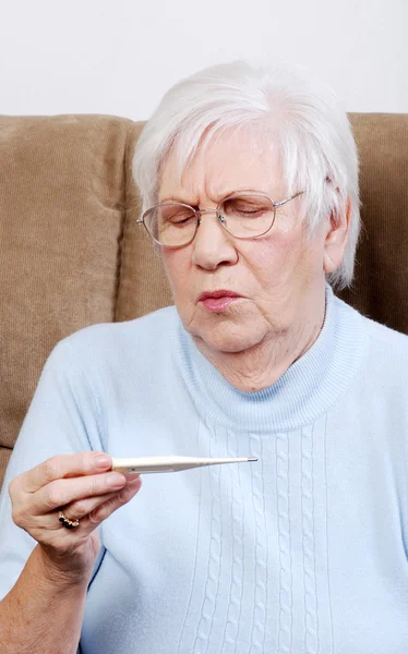 Ziek senior geschokt op haar temperatuur op thermometer — Stockfoto