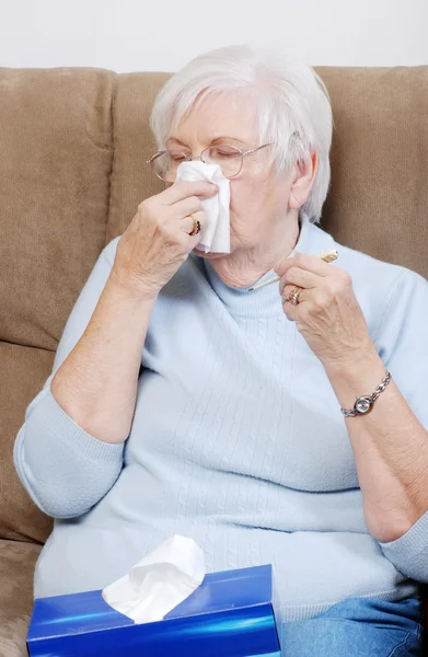 Sick senior with thermometer blowing her nose — Stock Photo, Image