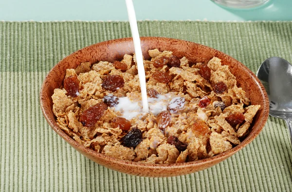 Milk pouring into bran and raisin cereal — Stock Photo, Image