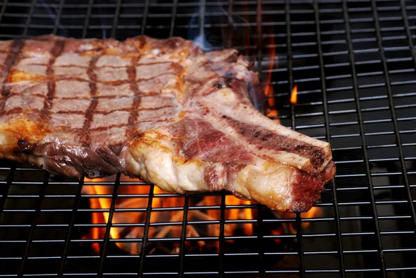 Bife de costela no churrasco com fumaça e chamas — Fotografia de Stock