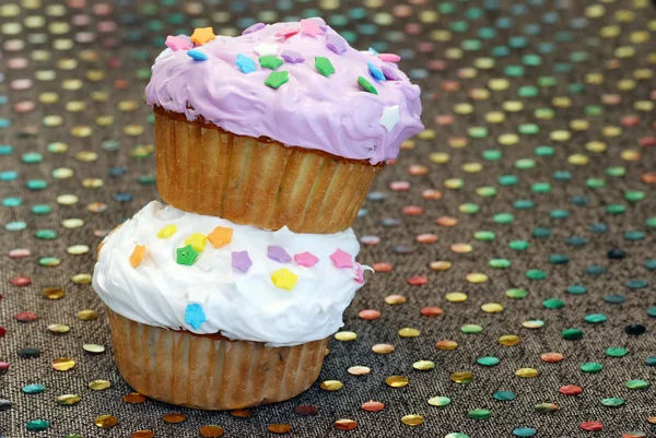 Στοιβάζονται cupcakes στο ζωηρόχρωμο τραπεζομάντιλο — Φωτογραφία Αρχείου