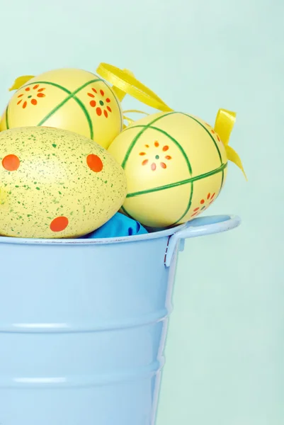 Yellow easter eggs in blue bucket — Stock Photo, Image