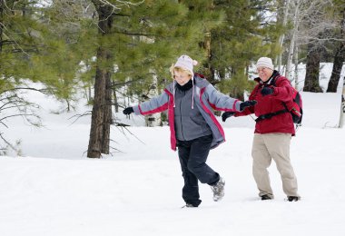 Active retired couple playing in the snow clipart