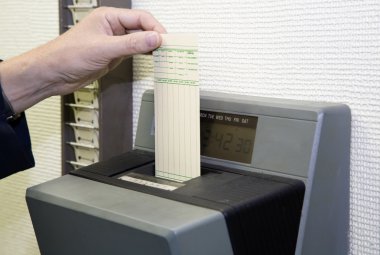 A worker is punching his time card with the automatic clock clipart