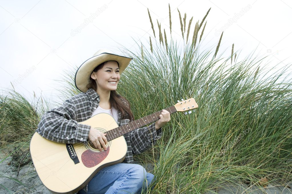 A shot of a beautiful woman playing guitar outside at the beach