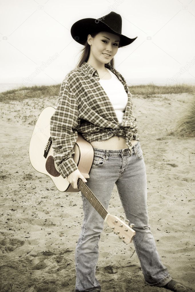 A portrait of a beautiful young woman carrying a guitar in sepia tone