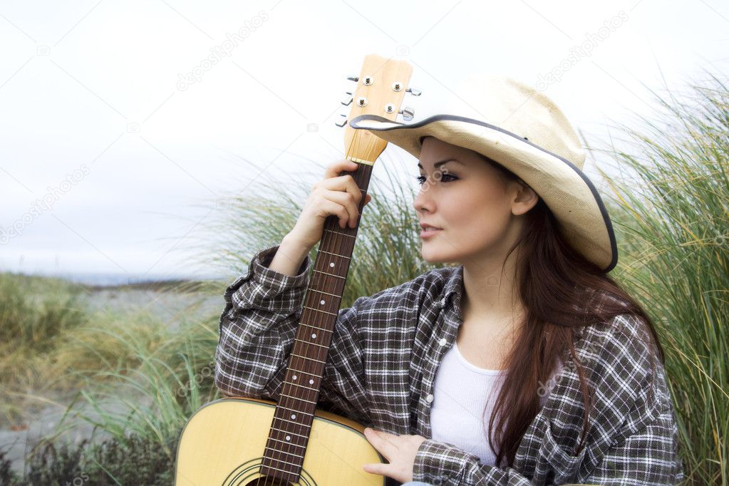 A beautiful girl posing with a guitar at the beach