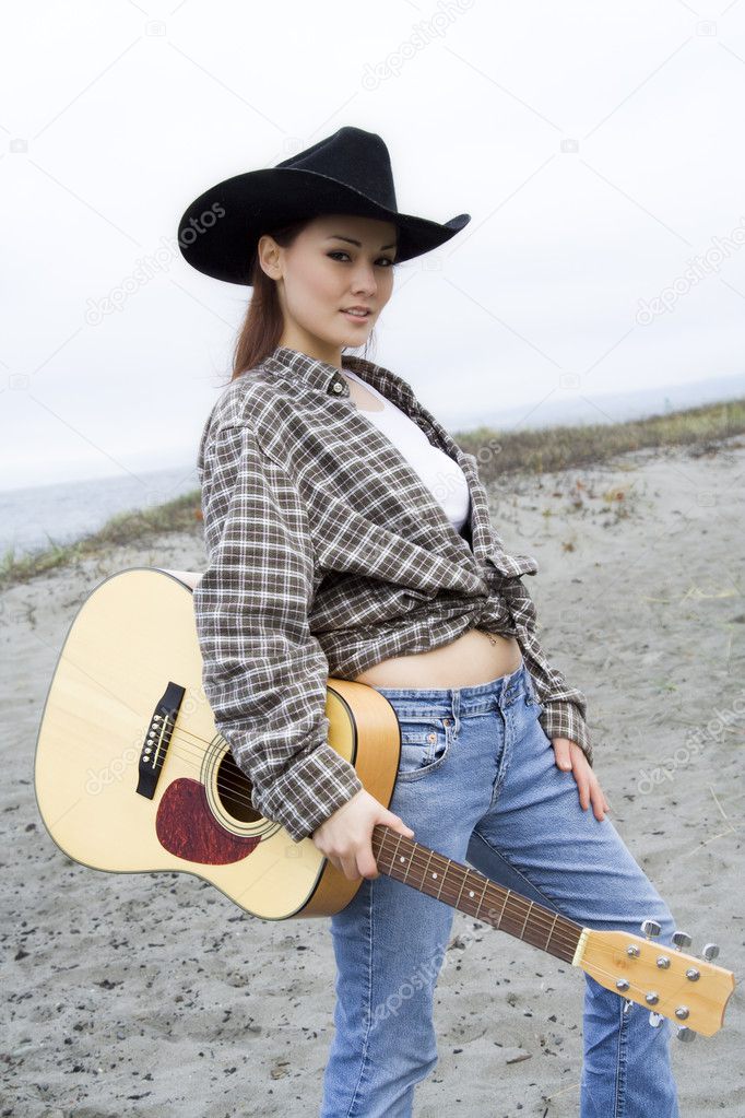 A beautiful young woman carrying a guitar at the beach