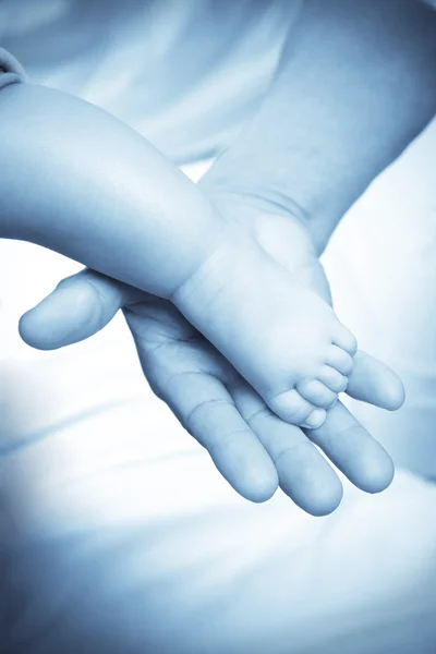 Pé de bebê e mão adulta — Fotografia de Stock