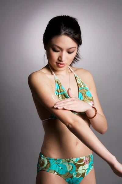 Asian woman applying lotion — Stock Photo, Image